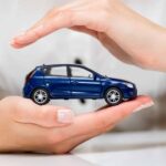 A man protecting a car with hands ensuring regular car inspections to prevent accidents